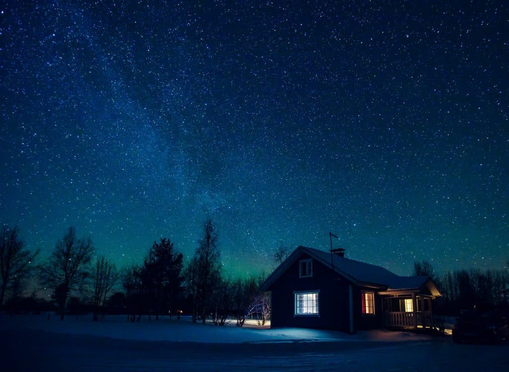 Cottage against the night sky with the Milky Way and the arctic Northern lights Aurora Borealis
