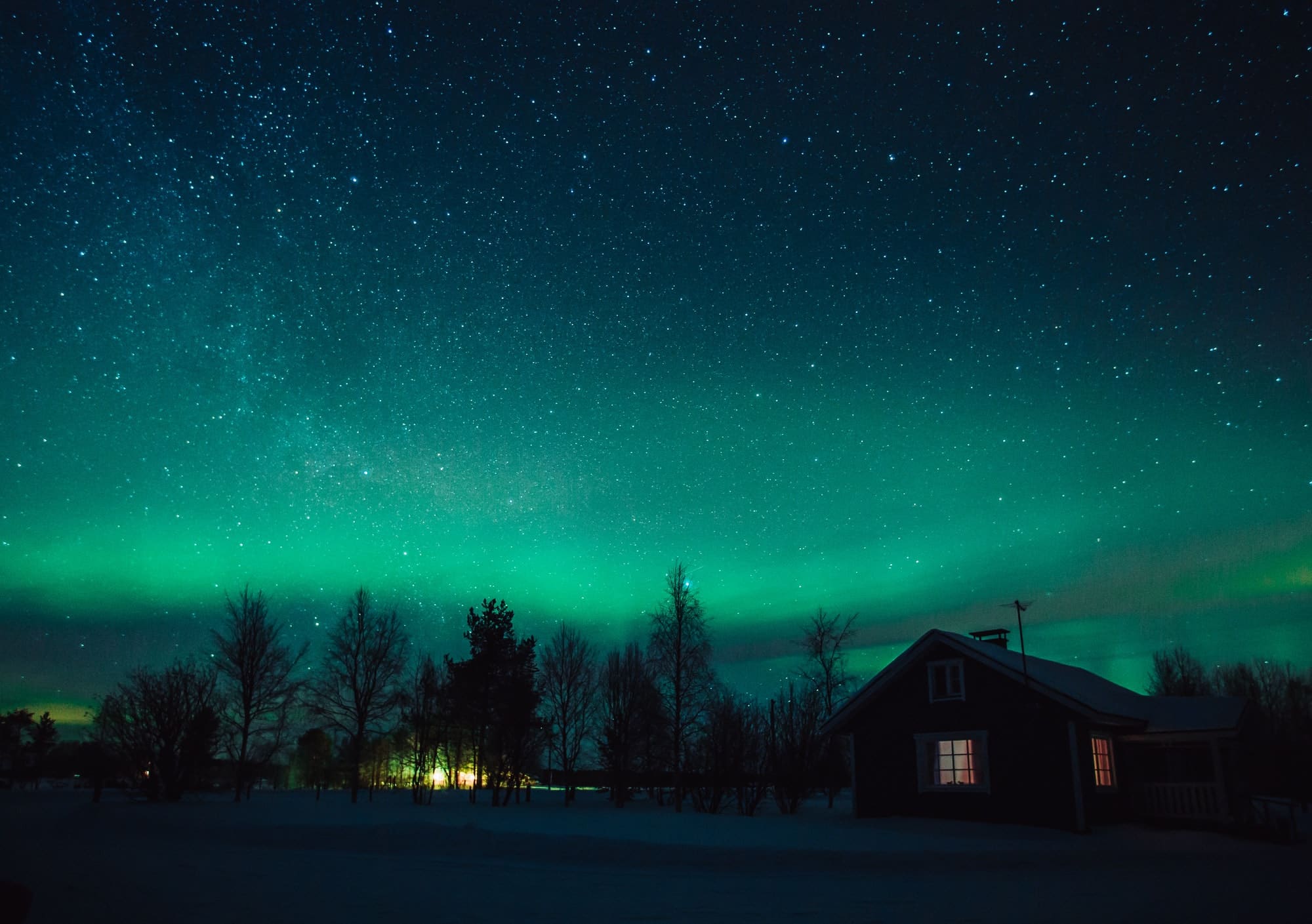 Northern lights (Aurora Borealis) over cottage in Lapland village. Finland